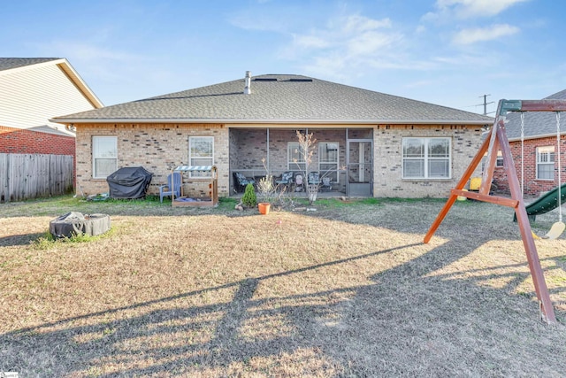 back of property with a playground, a sunroom, and a yard