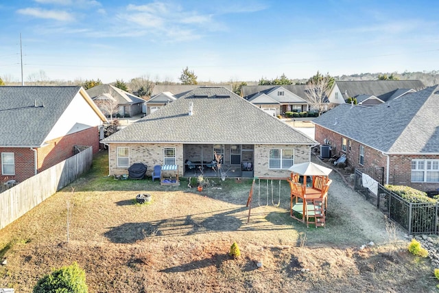 rear view of house featuring central AC unit, a yard, and a playground