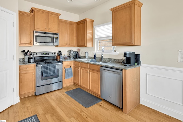 kitchen featuring stainless steel appliances, sink, and light hardwood / wood-style flooring