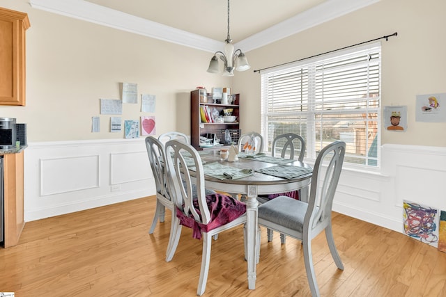 dining area featuring crown molding, a chandelier, and light hardwood / wood-style flooring