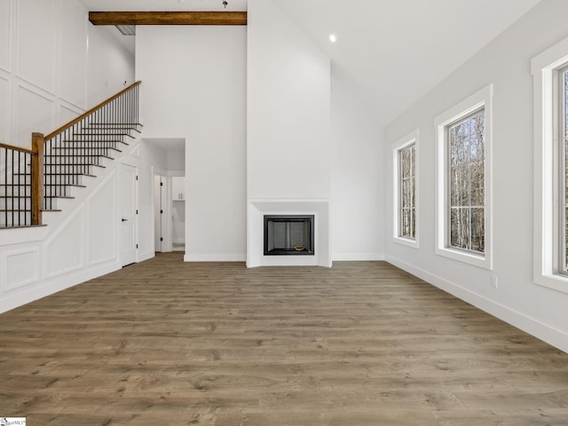 unfurnished living room featuring beamed ceiling, high vaulted ceiling, and light hardwood / wood-style flooring