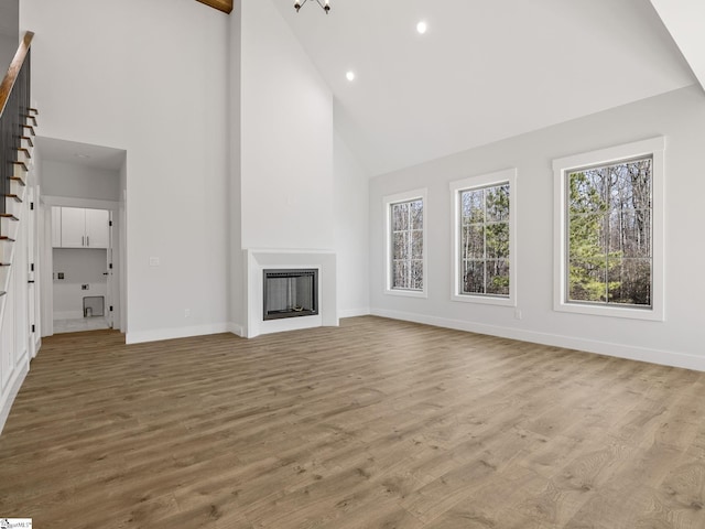 unfurnished living room featuring high vaulted ceiling and light hardwood / wood-style flooring