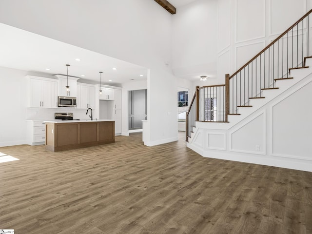 unfurnished living room featuring a high ceiling, dark hardwood / wood-style floors, and sink