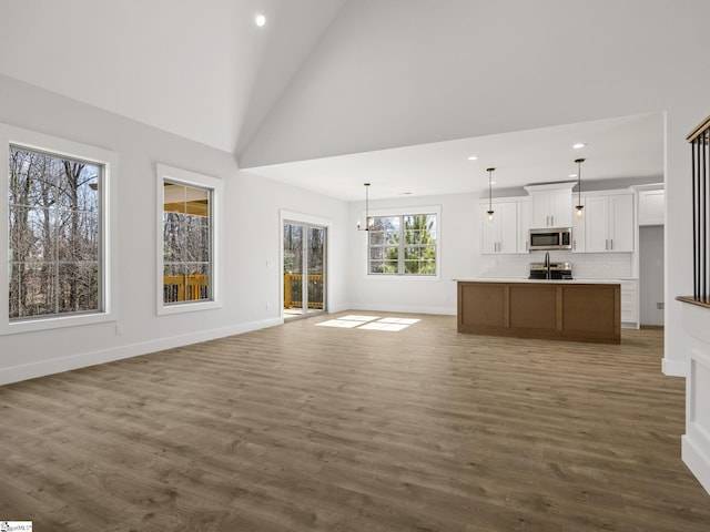 unfurnished living room featuring a notable chandelier, dark wood-type flooring, and high vaulted ceiling