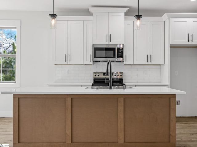 kitchen with hanging light fixtures, white cabinets, and appliances with stainless steel finishes