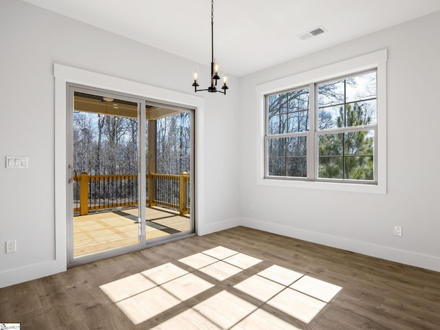 unfurnished dining area with hardwood / wood-style flooring and a notable chandelier