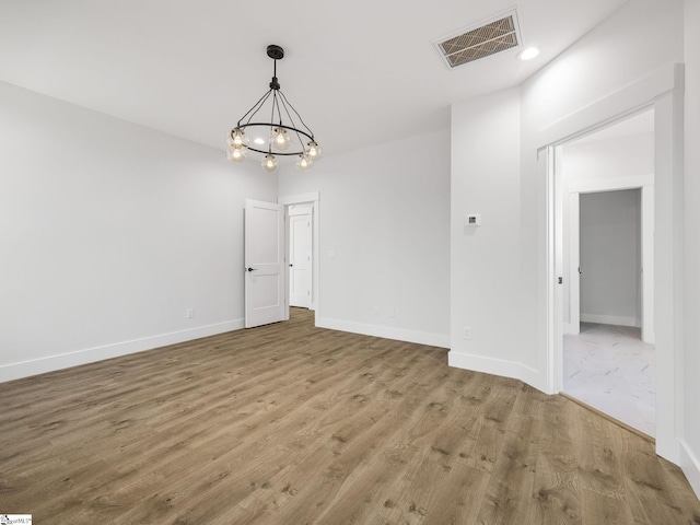 empty room featuring hardwood / wood-style flooring and a chandelier