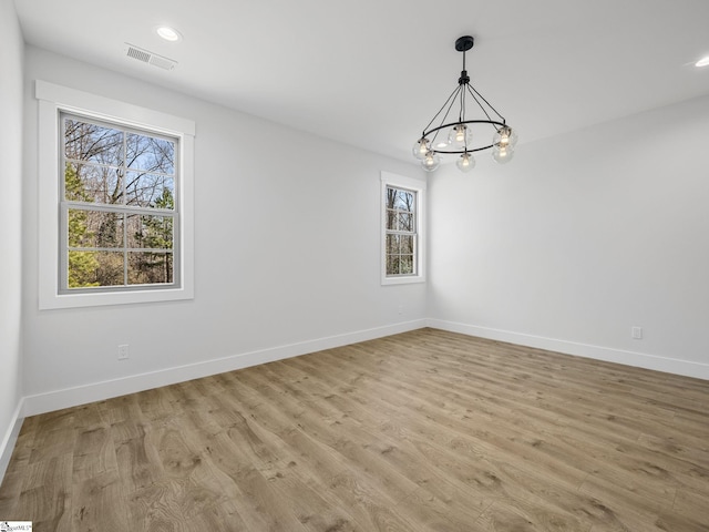 unfurnished room with an inviting chandelier and light hardwood / wood-style floors