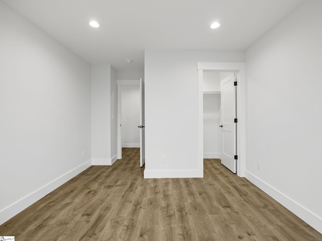 unfurnished bedroom with a spacious closet and light wood-type flooring