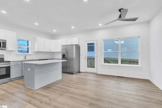 kitchen with tasteful backsplash, light hardwood / wood-style flooring, a kitchen island, stainless steel appliances, and white cabinets