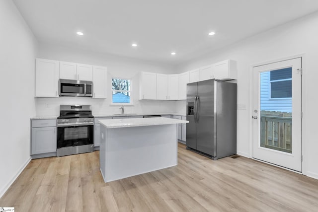 kitchen featuring a kitchen island, white cabinetry, sink, stainless steel appliances, and light wood-type flooring