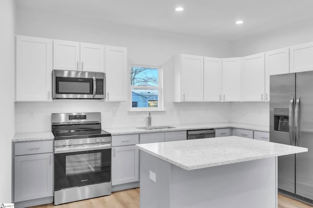 kitchen featuring sink, light stone counters, a center island, stainless steel appliances, and decorative backsplash