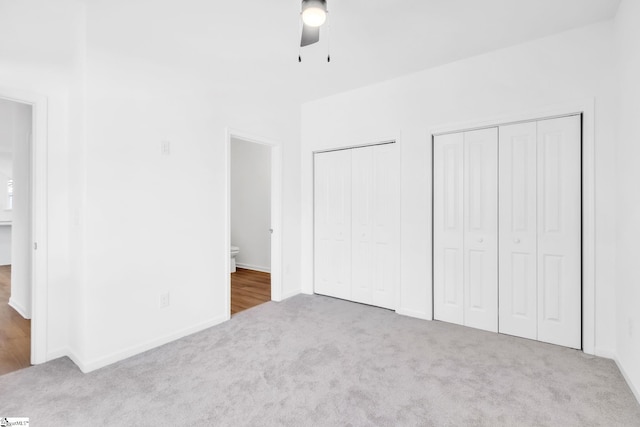 unfurnished bedroom with ceiling fan, ensuite bath, multiple closets, and carpet flooring