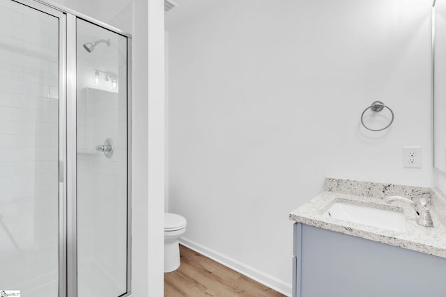 bathroom featuring vanity, wood-type flooring, a shower with door, and toilet