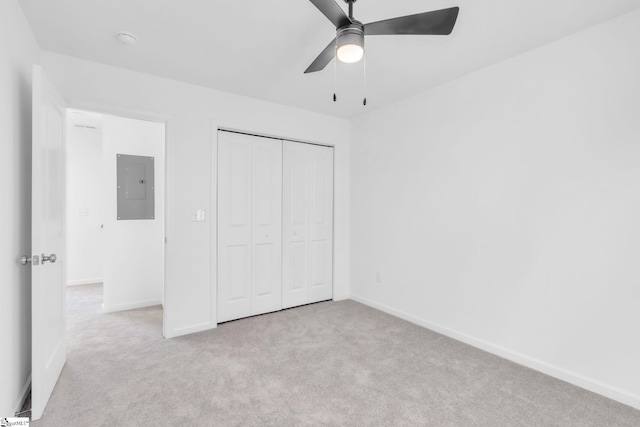 unfurnished bedroom featuring ceiling fan, a closet, electric panel, and light carpet