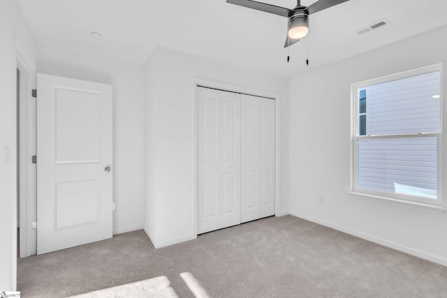 unfurnished bedroom with light carpet, a closet, and ceiling fan