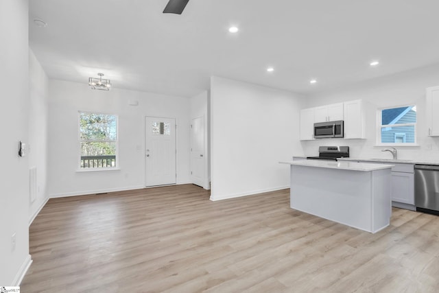 kitchen featuring white cabinetry, light wood-type flooring, a center island, and appliances with stainless steel finishes