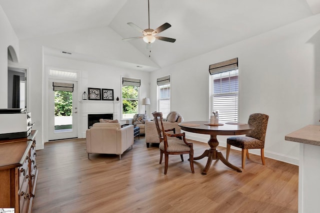 dining space with ceiling fan, high vaulted ceiling, and light hardwood / wood-style floors