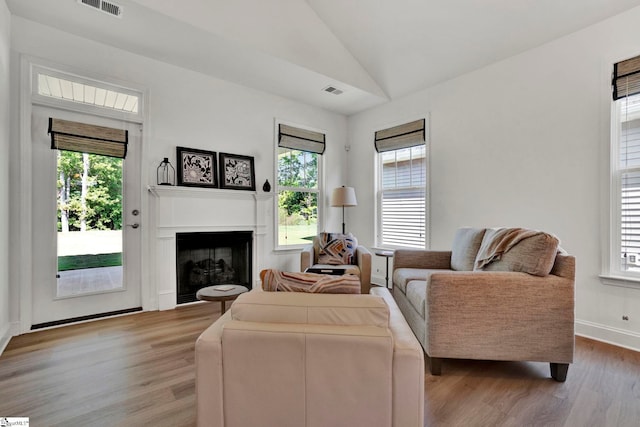 living room featuring lofted ceiling and light hardwood / wood-style flooring