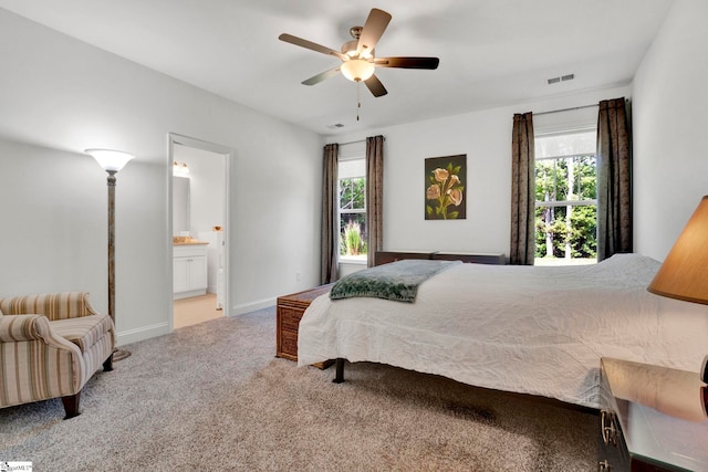 carpeted bedroom with multiple windows, ensuite bath, and ceiling fan