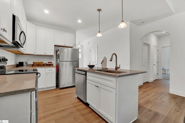 kitchen featuring pendant lighting, white cabinetry, sink, stainless steel appliances, and a center island with sink