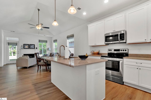 kitchen featuring white cabinetry, pendant lighting, stainless steel appliances, light stone countertops, and a kitchen island with sink