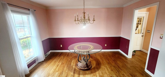 dining room with hardwood / wood-style flooring, a healthy amount of sunlight, and a notable chandelier