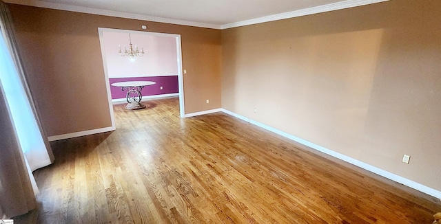 spare room with ornamental molding, hardwood / wood-style floors, and a notable chandelier