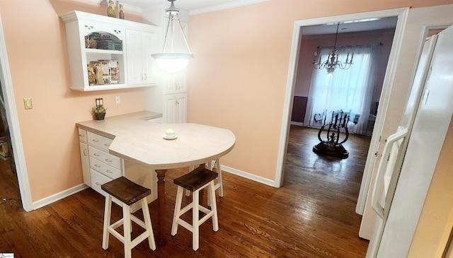 dining space featuring dark wood-type flooring, ornamental molding, and a chandelier