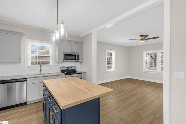 kitchen with blue cabinetry, sink, appliances with stainless steel finishes, plenty of natural light, and a kitchen island