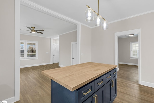 kitchen featuring crown molding, blue cabinets, hanging light fixtures, and a kitchen island