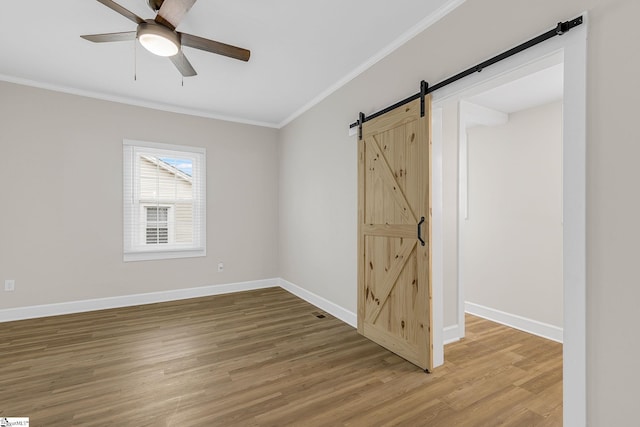 unfurnished room featuring crown molding, hardwood / wood-style flooring, and a barn door