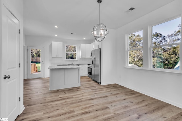 kitchen with decorative light fixtures, tasteful backsplash, white cabinets, a center island, and stainless steel appliances