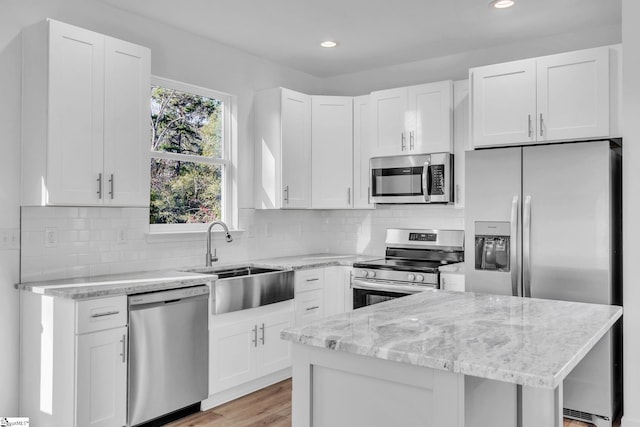 kitchen with sink, stainless steel appliances, white cabinets, and light stone countertops