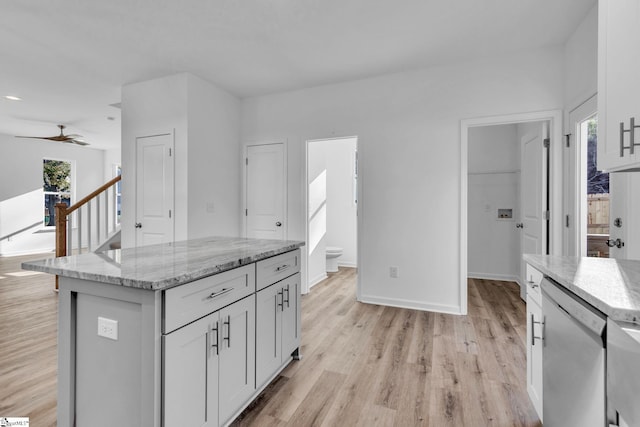 kitchen featuring light stone counters, light wood-type flooring, dishwasher, and a kitchen island