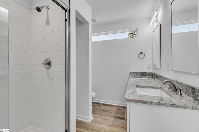 bathroom featuring vanity, hardwood / wood-style flooring, toilet, and tiled shower