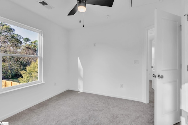 unfurnished room featuring a healthy amount of sunlight, light colored carpet, and ceiling fan