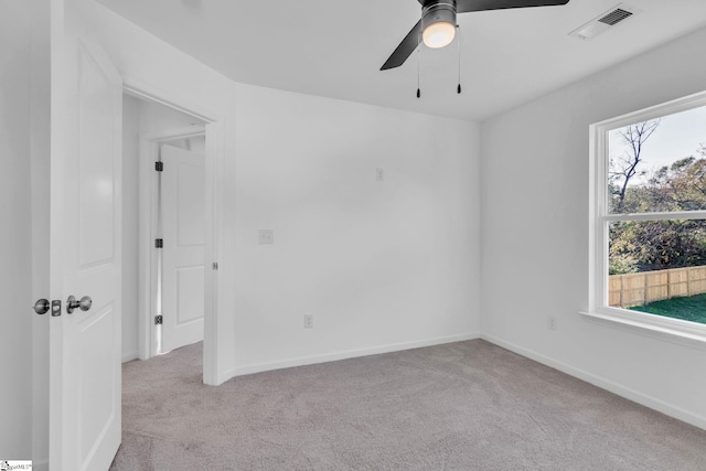 carpeted spare room featuring plenty of natural light and ceiling fan