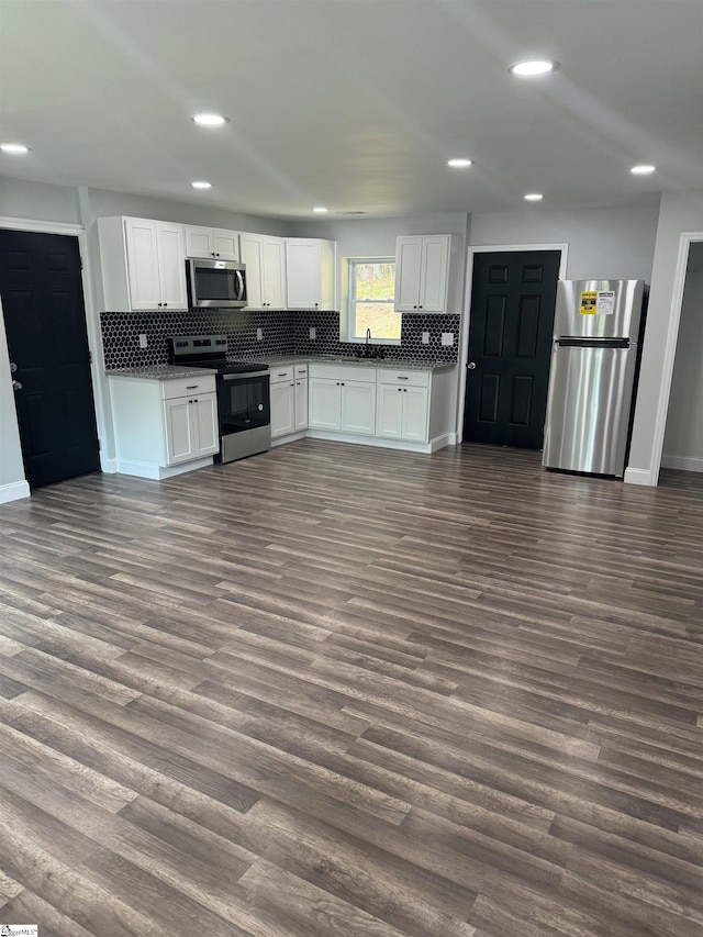 kitchen with stainless steel appliances, tasteful backsplash, white cabinets, and dark hardwood / wood-style flooring