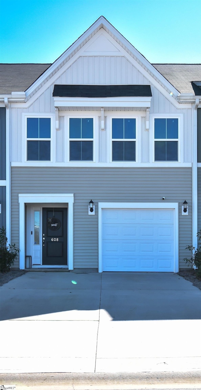 view of front of home with an attached garage, a shingled roof, board and batten siding, and concrete driveway