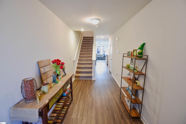 hall featuring stairs, dark wood-style floors, and baseboards