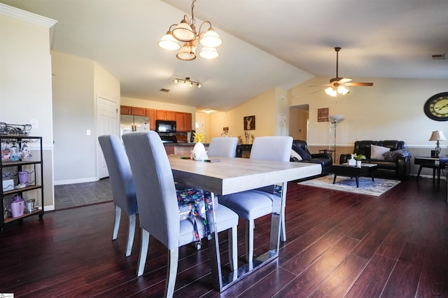 dining area featuring dark wood-type flooring, ceiling fan with notable chandelier, and vaulted ceiling