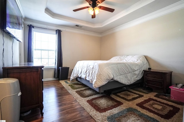 bedroom featuring crown molding, a tray ceiling, dark hardwood / wood-style floors, and ceiling fan