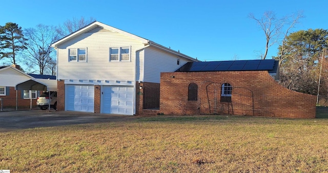 back of house featuring brick siding, aphalt driveway, a lawn, and a garage