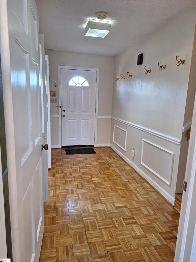entryway featuring a decorative wall, a wainscoted wall, and a textured ceiling