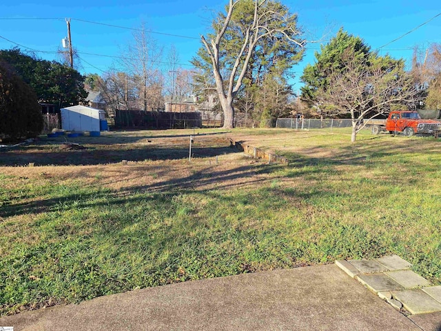 view of yard featuring an outbuilding, a storage unit, and fence
