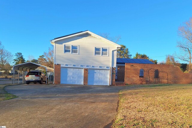 view of side of home featuring a lawn, concrete driveway, a garage, brick siding, and solar panels