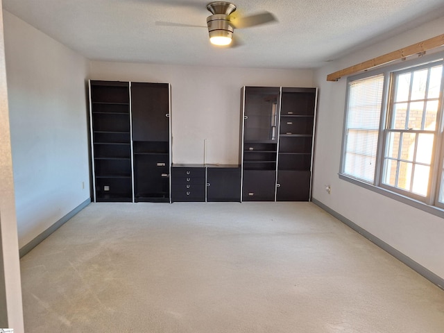 unfurnished bedroom featuring ceiling fan, light colored carpet, and a textured ceiling