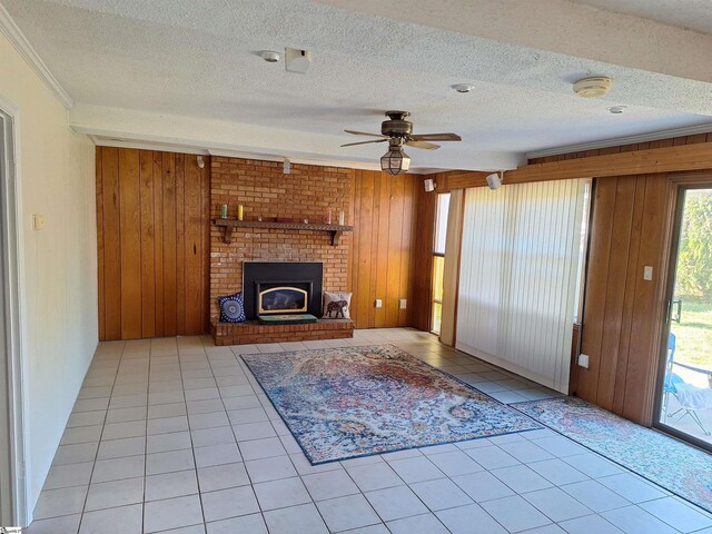 unfurnished living room featuring a textured ceiling, wooden walls, ceiling fan, and tile patterned flooring