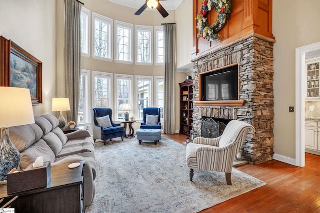 living room featuring wood-type flooring, a fireplace, and a high ceiling